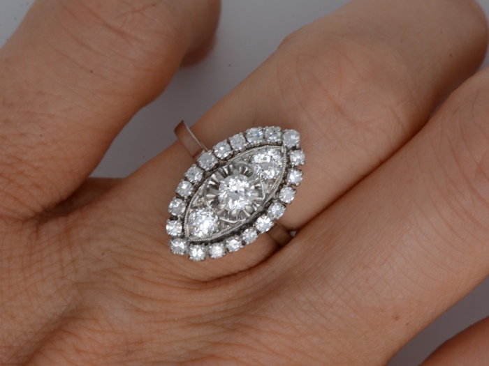 Détail d’une bague Art Déco ancienne en or gris et diamants portée au doigt.