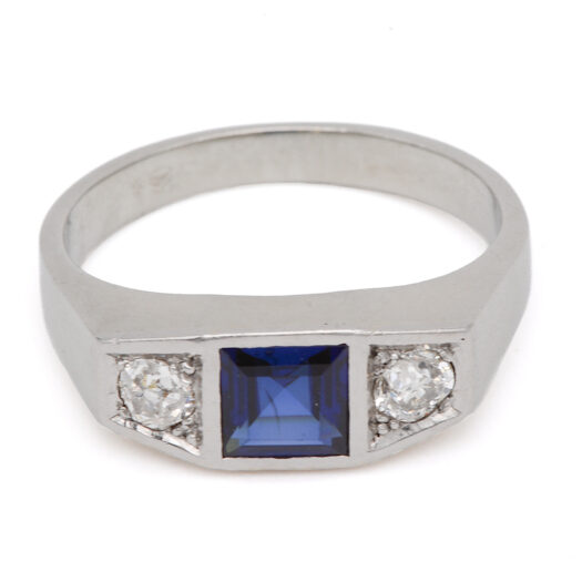 Bague jarretière Art Déco à pierre bleue sertie clos et deux diamants taille ancienne, vue de face